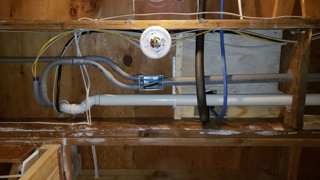 A smoke detector bracket mounted in a basement ceiling