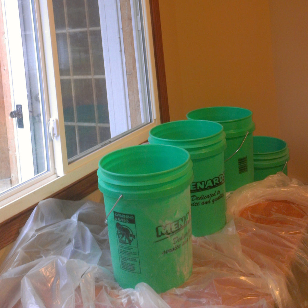 Sheets of plastic and several buckets catch melt water from ice dam damage to a bedroom soffit.